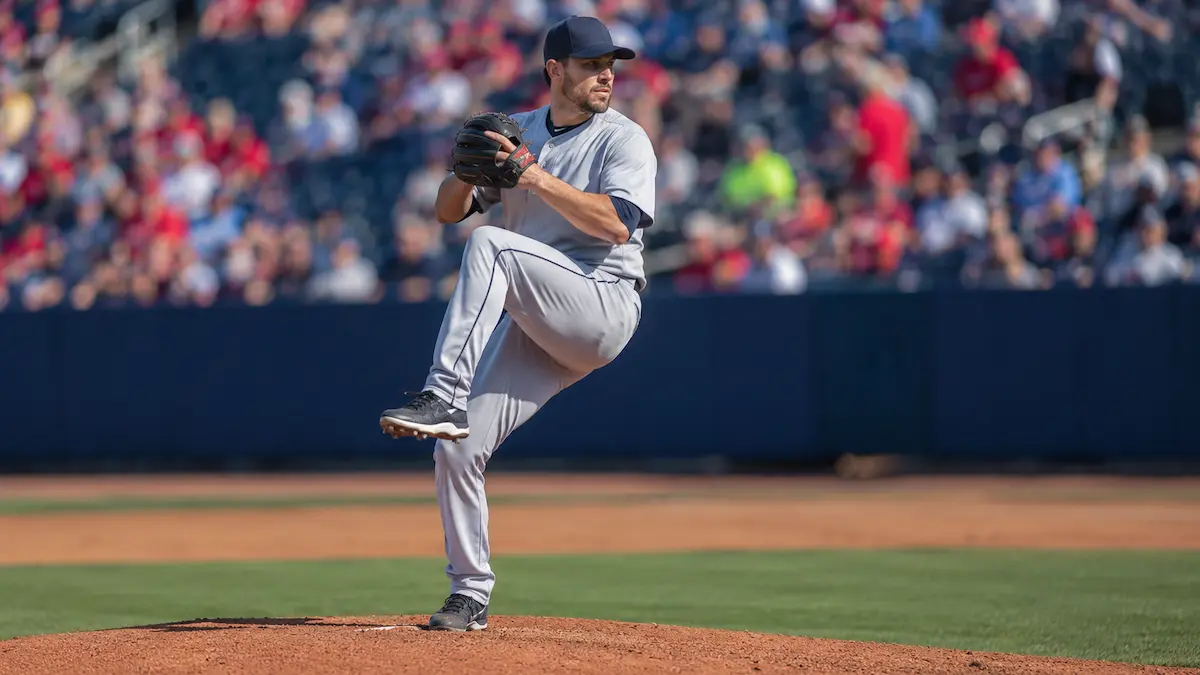 Adult amateur baseball pitcher mid-windup on the mound